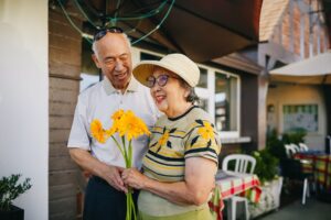 Pareja de abuelos sonriendo con un ramo de flores amarillas