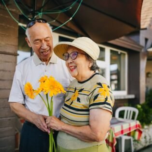 Pareja de abuelos sonriendo con un ramo de flores amarillas