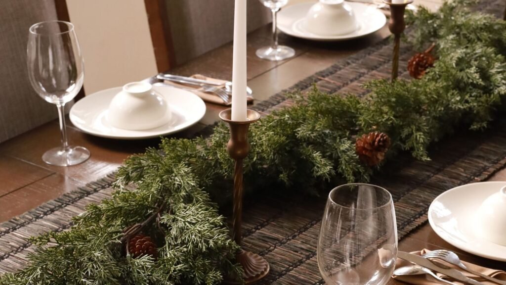 Mesa de Navidad con una guirnalda baja de verde y velas en el centro, a una altura que no tapa la cara de los comensales