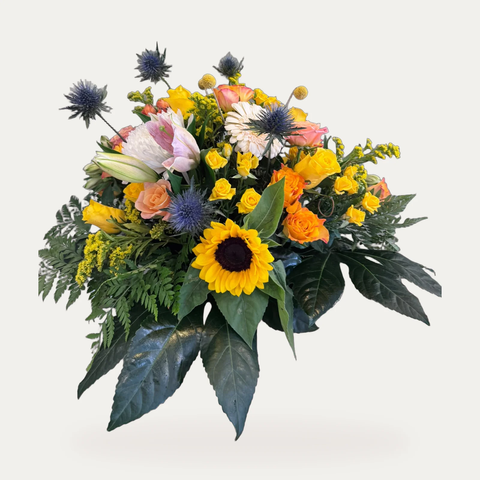 Centro de girasoles, rosas naranjas y amarillas, lirio y cardo azul